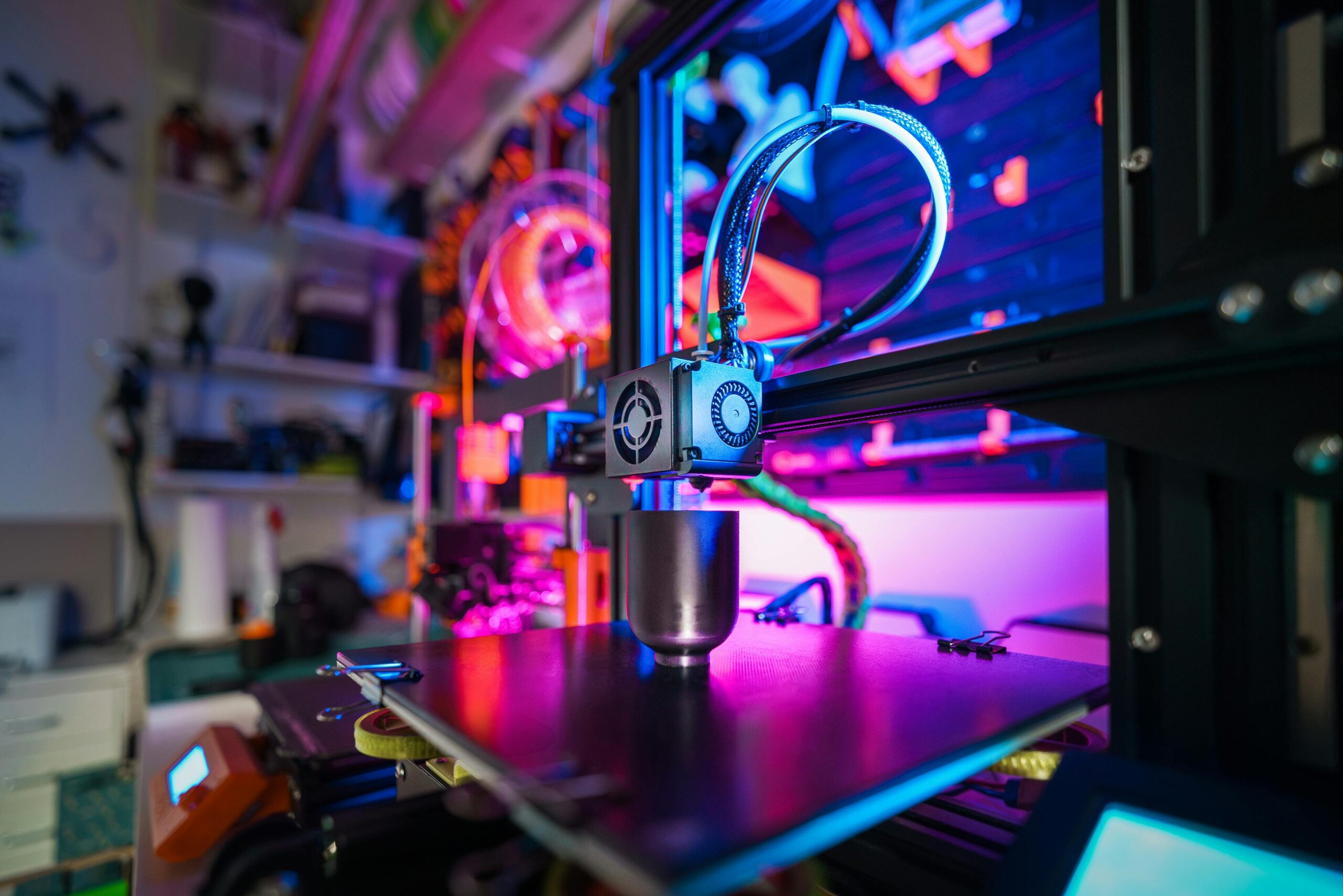 Close-up of a 3D printer's extruder in action, with neon backlighting adding a futuristic glow to the precise mechanical movements of the machine.