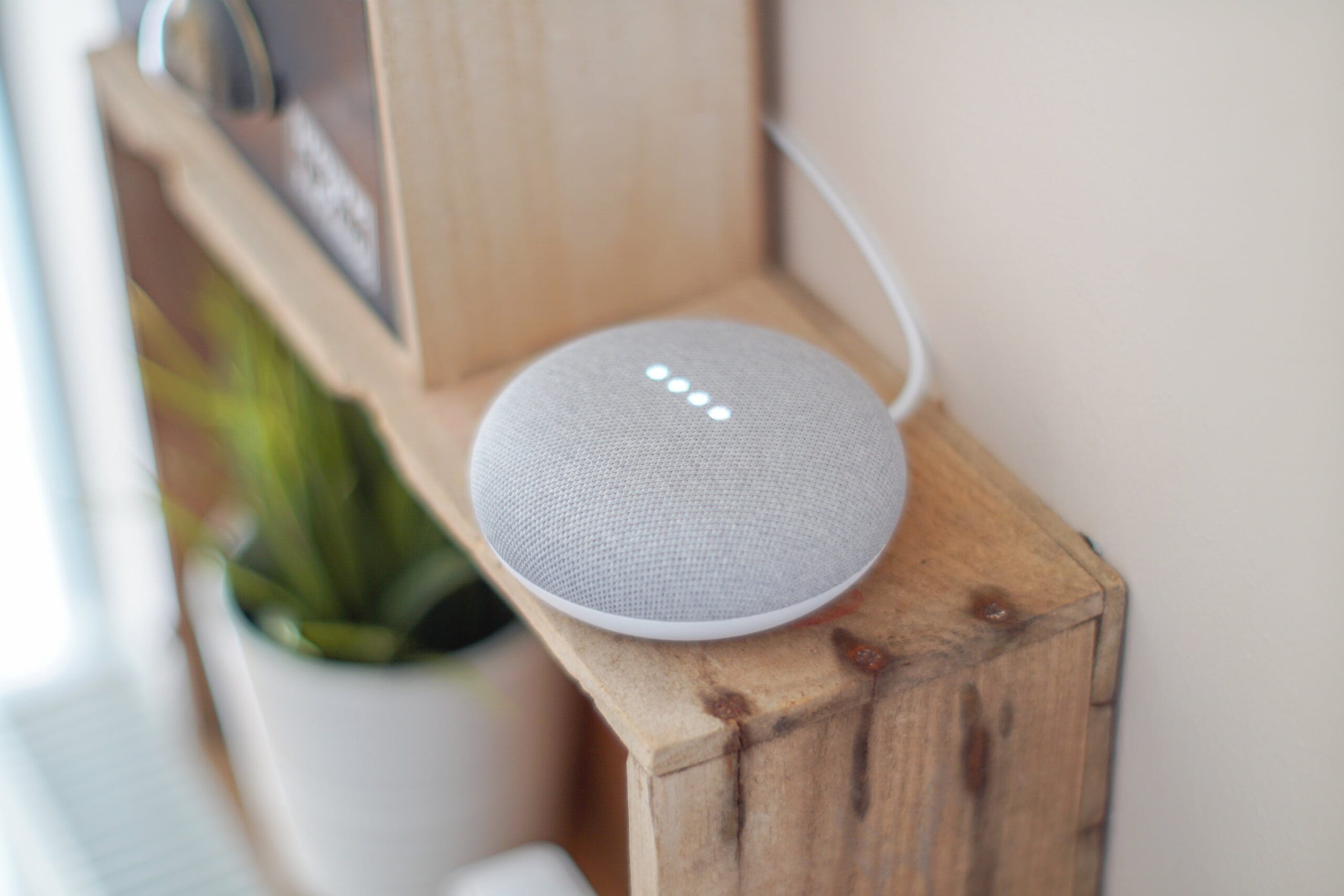 A smart speaker on a rustic wooden shelf, illuminated by soft light, showcasing modern smart home technology in a cozy setting.