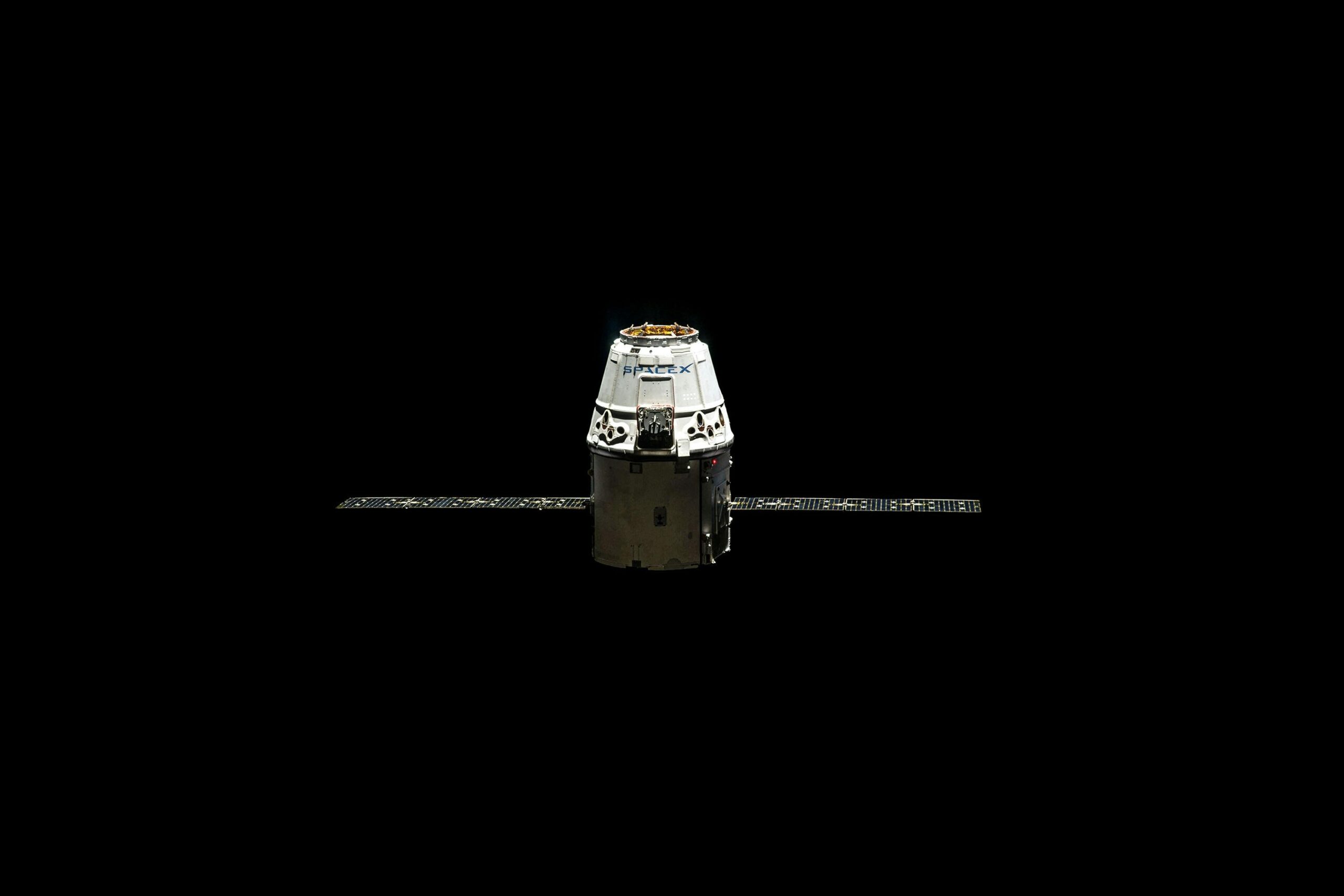 Space X Crew Dragon spacecraft isolated on a black background with solar panels extended, representing modern space travel and exploration.